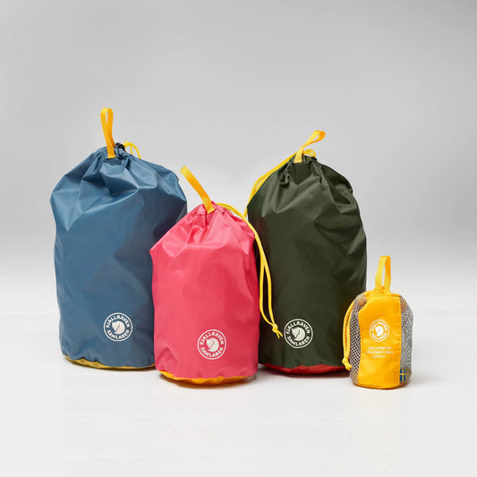 Four drawstring bags in blue, pink, green, and yellow with a brand logo on a gray background.